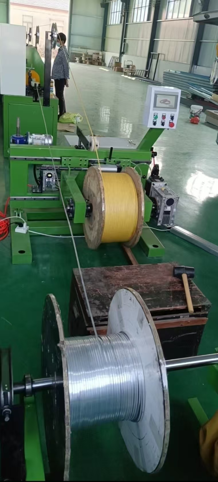 Covered-wire production equipment on the Shuangyou factory floor with control panel, operator and conductor spools